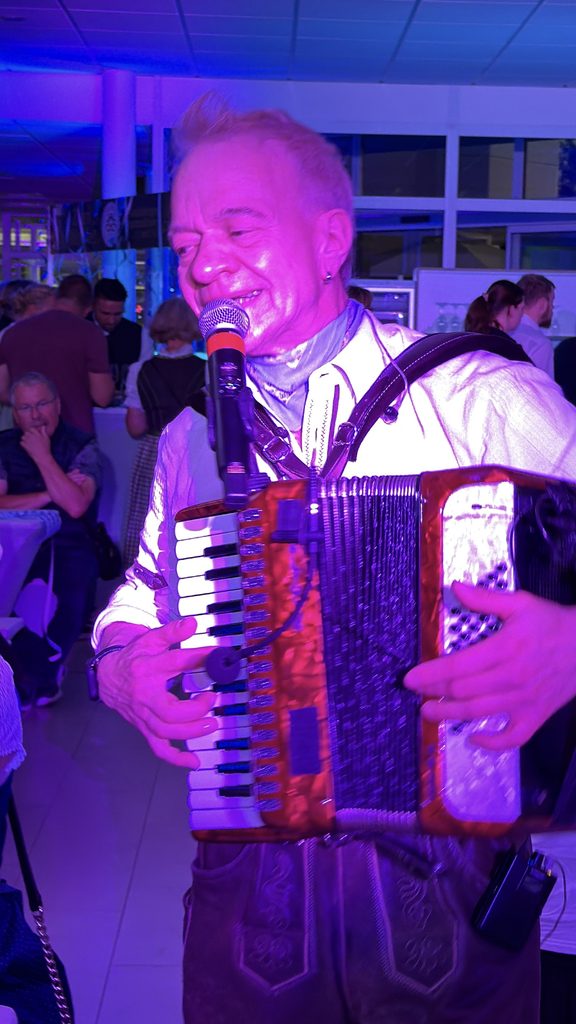 Akkordeonist spielt live zwischen den Gästen beim Firmenoktoberfest